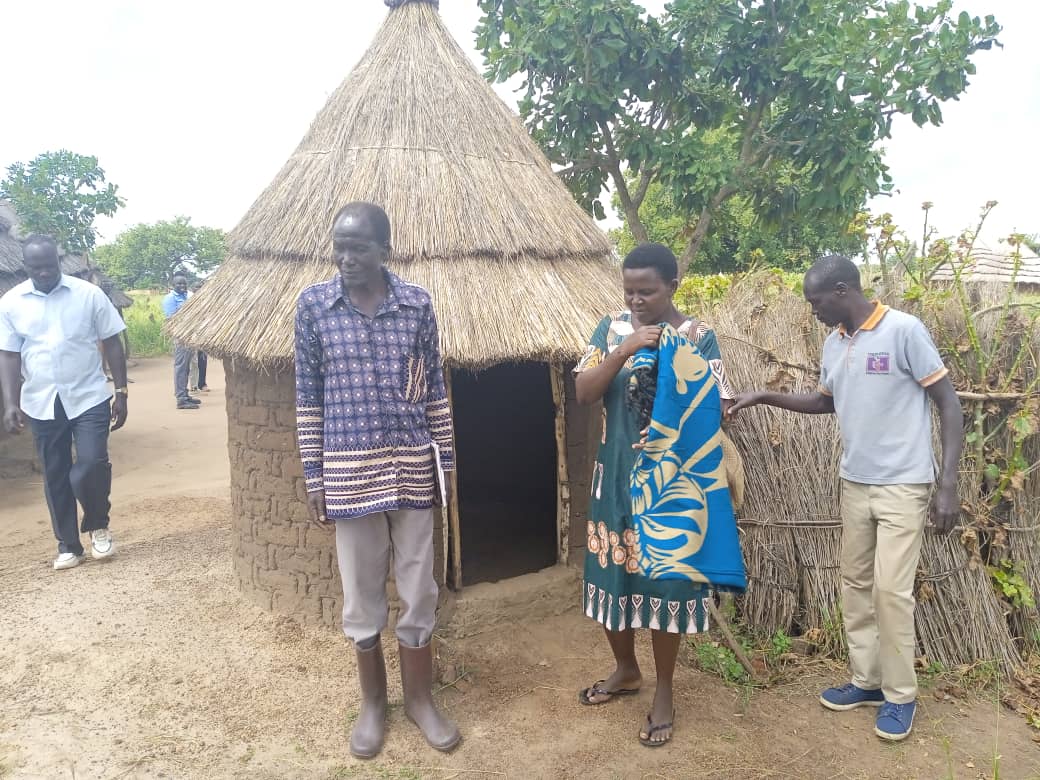 Emmanuel Ojirot, the deputy RDC of Kapelebyong handing over the site to the contractor Miria Atia, the vice District Chairperson of Kapelebyong monitoring the state of sanitation of households in the district recently. Photo by Emmanuel Opio.jpg